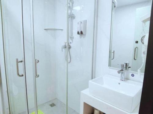 a white bathroom with a sink and a shower at 7 Days Inn Guilin Beiji Plaza Yushan Garden in Guilin