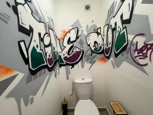 a bathroom with a toilet with graffiti on the wall at L'urban street Cayenne in Cayenne