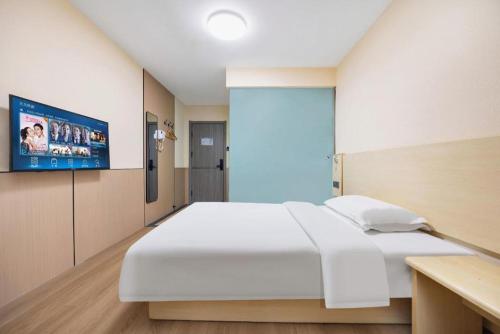 a bedroom with a large white bed and a flat screen tv at 7 Days Inn Baoding Railway Station in Baoding