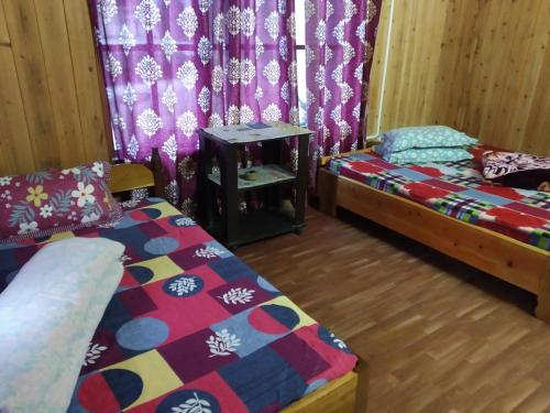1 Schlafzimmer mit 2 Betten, einem Tisch und Vorhängen in der Unterkunft EHI Homestay Rishop in Rishop