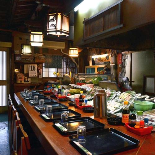 a kitchen with a long counter with food on it at Hamakan Hotel in Unzen