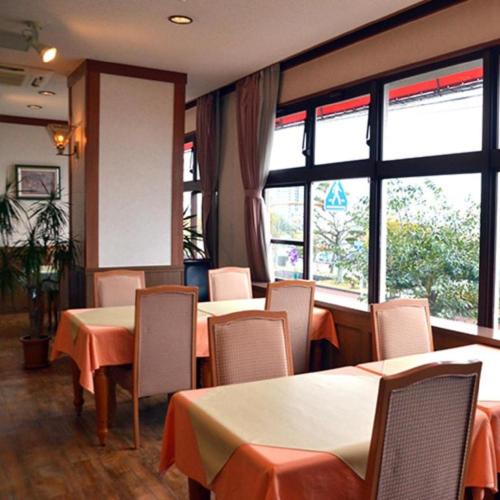 a restaurant with tables and chairs and windows at Hamakan Hotel in Unzen