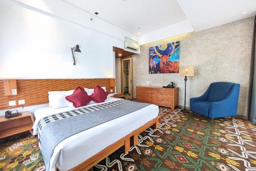 a hotel room with a bed and a blue chair at THE 1O1 Bandung Dago in Bandung