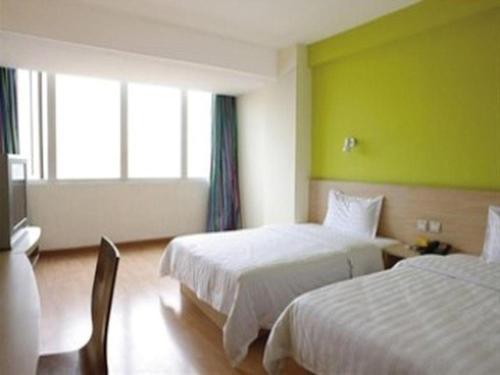 a hotel room with two beds and a green wall at 7 Days Inn Yiyang Shengli Road in Shangrao