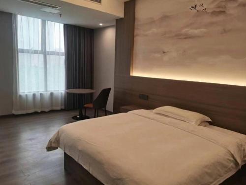 a bedroom with a large bed and a table at GreenTree Alliance Anhui Hefei South Passenger Station South High Speed Railway Station Hotel in Hefei