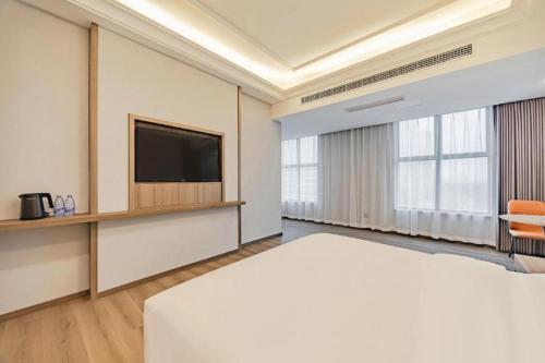 a hotel room with a bed and a flat screen tv at GreenTree Alliance Anhui Hefei South Passenger Station South High Speed Railway Station Hotel in Hefei