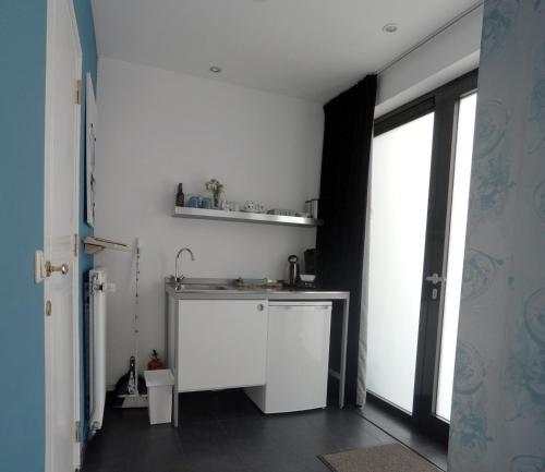 a white kitchen with a sink and a window at Het blauwe huis in Reuver