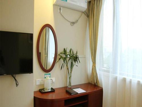 a room with a television and a table with a mirror at GreenTree Inn Nanjing Confucius Temple Sanshan Street Subway Station Express Hotel in Nanjing