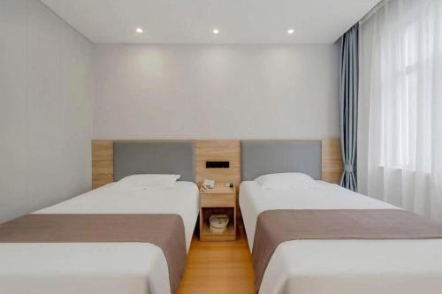 a hotel room with two beds and a desk at GreenTree Inn Nanjing Confucius Temple Sanshan Street Subway Station Express Hotel in Nanjing
