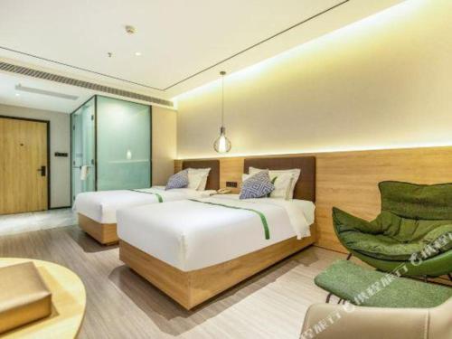 una habitación de hotel con dos camas y una silla en GreenTree Inn Shandong Jinan Suncun New District Express Hotel, en Jinan