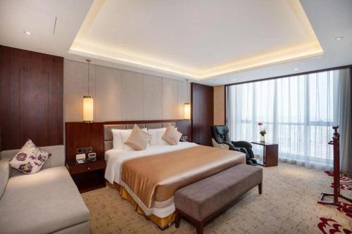 a hotel room with a large bed and a chair at New Century Grand Hotel Xi'an Xizang Building in Xi'an