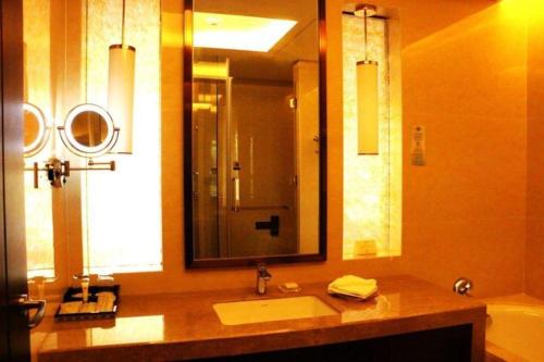 a bathroom with a sink and a large mirror at New Century Grand Hotel Xi'an Xizang Building in Xi'an
