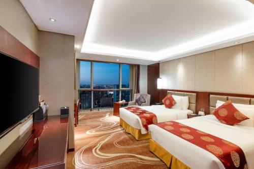 a hotel room with two beds and a flat screen tv at New Century Grand Hotel Xi'an Xizang Building in Xi'an