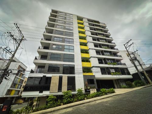 a tall apartment building with yellow and white at Loft Industrial ubicación ideal in Armenia
