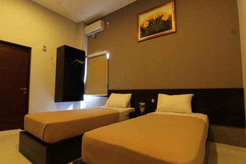 a hotel room with two beds and a picture on the wall at MANDARI HOTEL SINGARAJA in Ubud