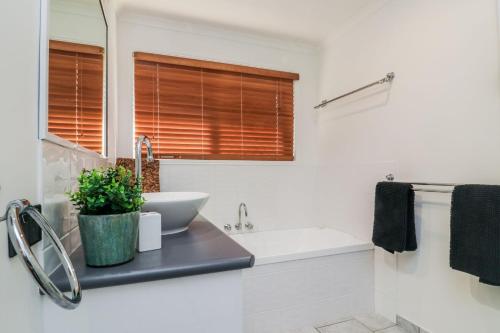 a white bathroom with a sink and a tub and a sink at Cabbage Palm Lodge - air conditioned home in town area in Agnes Water