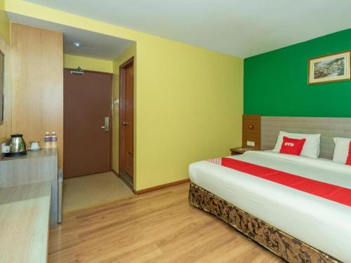 a bedroom with a large bed and a green wall at Capital O 89538 Ocean Hotel in Labuan