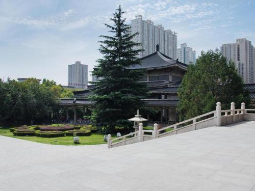 a pine tree in front of a building with a fence at Pai Hotel Xi'an Electronic Zheng Street in Xi'an
