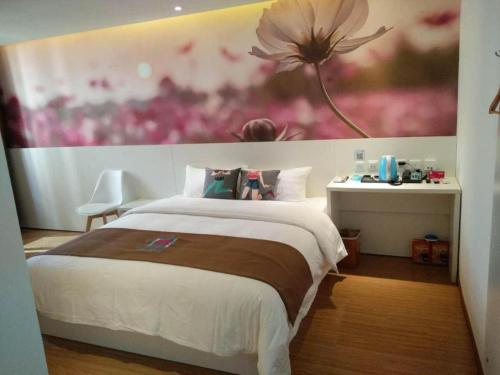 a bedroom with a large bed with a flower painting on the wall at Pai Hotel Yanjiao Tianyang Plaza in Gaolou