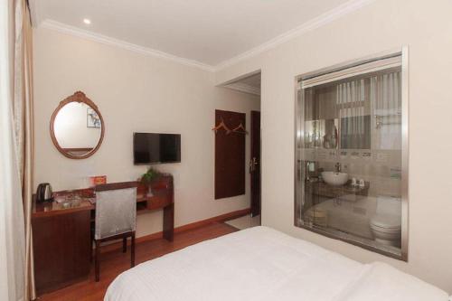 GreenTree Inn Wuxi Donggang Town Donghutang Shell Hotel في ووشي: غرفة نوم بها سرير ومكتب ومرآة