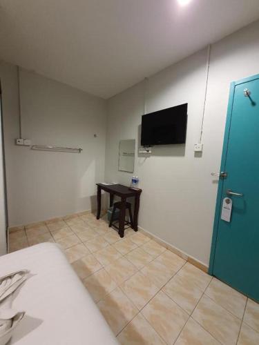 a room with a bed and a table and a tv at De Chukai Hotel in Cukai