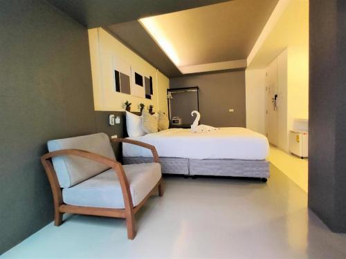 a bedroom with a large bed and a chair at Silom Studios in Bangkok