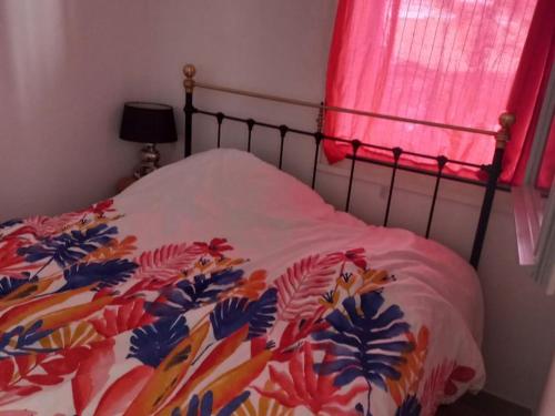 - un lit avec une couette colorée et une fenêtre dans l'établissement Appartement à Noirmoutier, proche plage, animaux admis, parking - FR-1-823-140, à Noirmoutier-en-l'lle