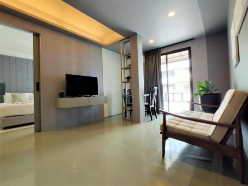 a living room with a tv and a couch and a chair at Silom Studios in Bangkok