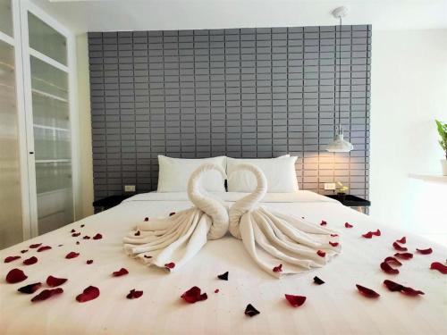 two white swans laying on a bed with roses at Silom Studios in Bangkok