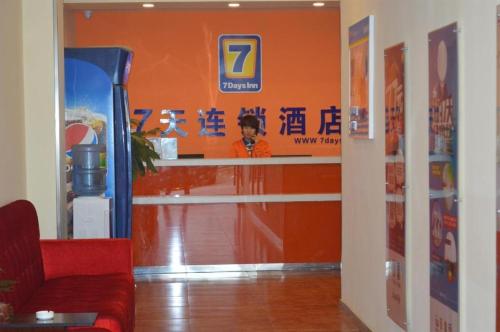 an orange wall with a man standing at a counter at 7 Days Inn Suzhou Mudu Ancient Town Kaima Auto Market in Suzhou