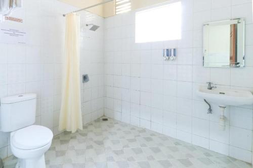 a white bathroom with a toilet and a sink at Andrin Daspatt Family Inn in Makassar