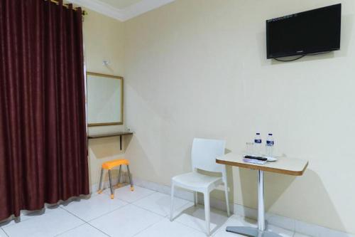 a room with a desk and a television on a wall at Andrin Daspatt Family Inn in Makassar