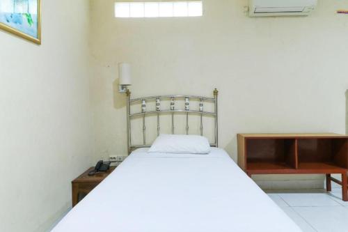 a bedroom with a white bed and a wooden table at Andrin Daspatt Family Inn in Makassar
