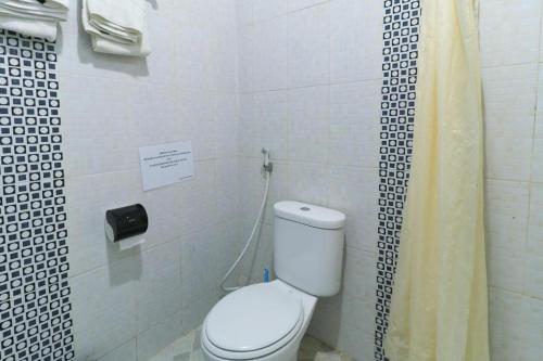 a bathroom with a toilet and a shower curtain at Andrin Daspatt Family Inn in Makassar