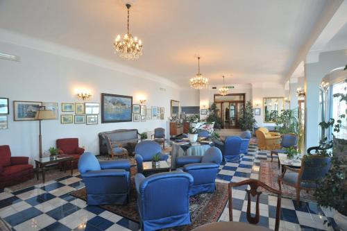 a lobby with blue chairs and tables and chandeliers at Hotel Belvedere in Conca dei Marini