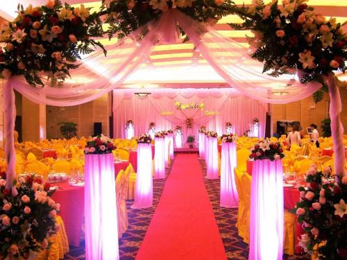 a wedding hall with pink and yellow flowers and a red aisle at Chaozhou Hotel in Chaozhou