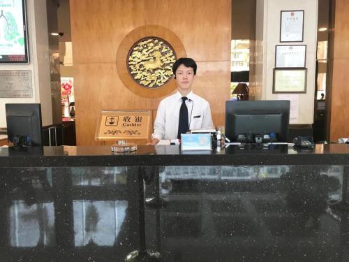 a man standing behind a counter in a restaurant at Chaozhou Hotel in Chaozhou