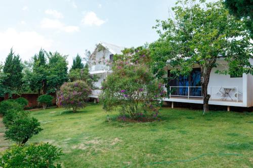 a white house with a yard with trees and bushes at La Maison Dalat in Ấp Man Ling