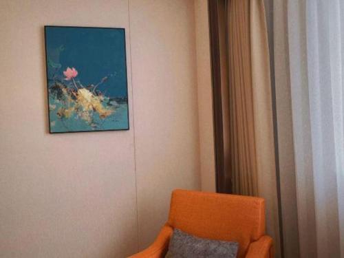 an orange chair in a room with a painting on the wall at Chaozhou Hotel in Chaozhou
