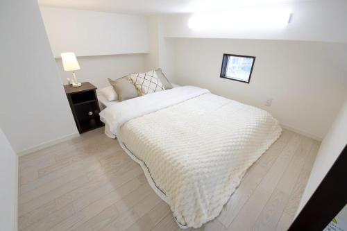 a white bedroom with a bed and a lamp at Isole le Olena 4F in Naha