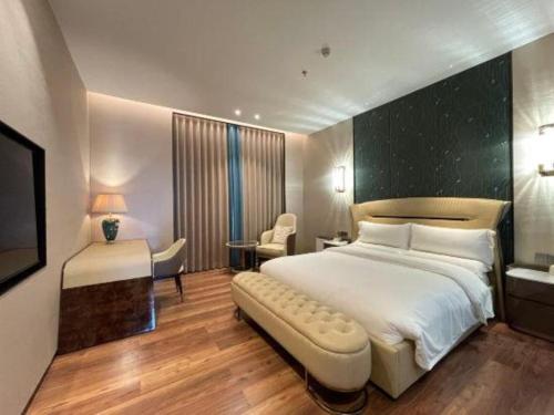 a bedroom with a large white bed and a desk at Chaozhou Hotel in Chaozhou