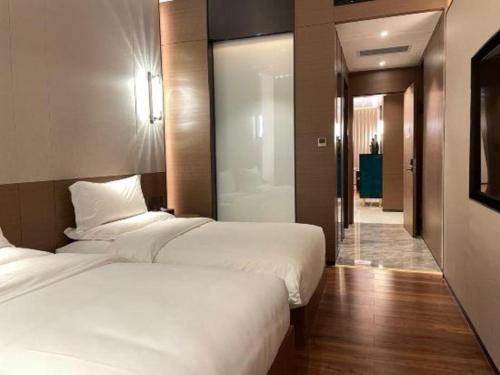 two beds in a hotel room with a hallway at Chaozhou Hotel in Chaozhou