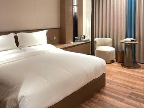 a bedroom with a large white bed and a chair at Chaozhou Hotel in Chaozhou