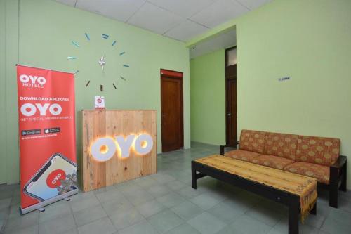 a room with a couch and a clock on the wall at Super OYO 1046 Omah Pathok in Yogyakarta