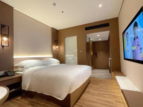 a bedroom with a large bed and a flat screen tv at Chaozhou Hotel in Chaozhou