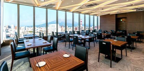 a restaurant with tables and chairs and a view of the city at Hotel Gran Cerezo Kagoshima in Kagoshima