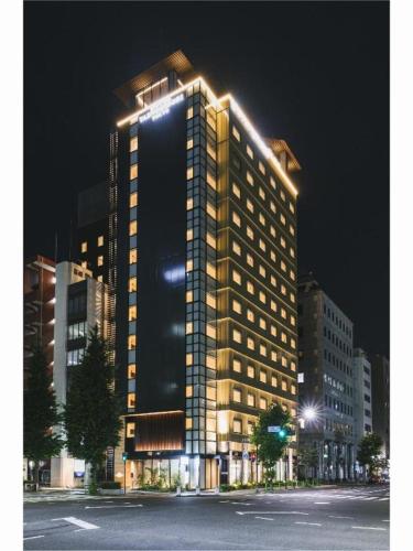 a tall building with lights on it at night at Hotel Yaenomidori Tokyo in Tokyo