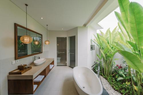 a bathroom with two sinks and a tub and a plant at Arpana Luxury Private Pool Villas in Jimbaran