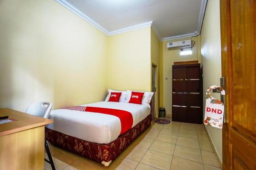 una camera da letto con letto con cuscini rossi e scrivania di OYO 1720 A2b Residence a Manado
