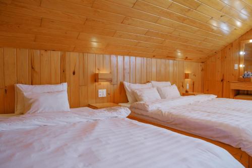 two beds in a room with wooden walls and ceilings at La Maison Dalat in Ấp Man Ling